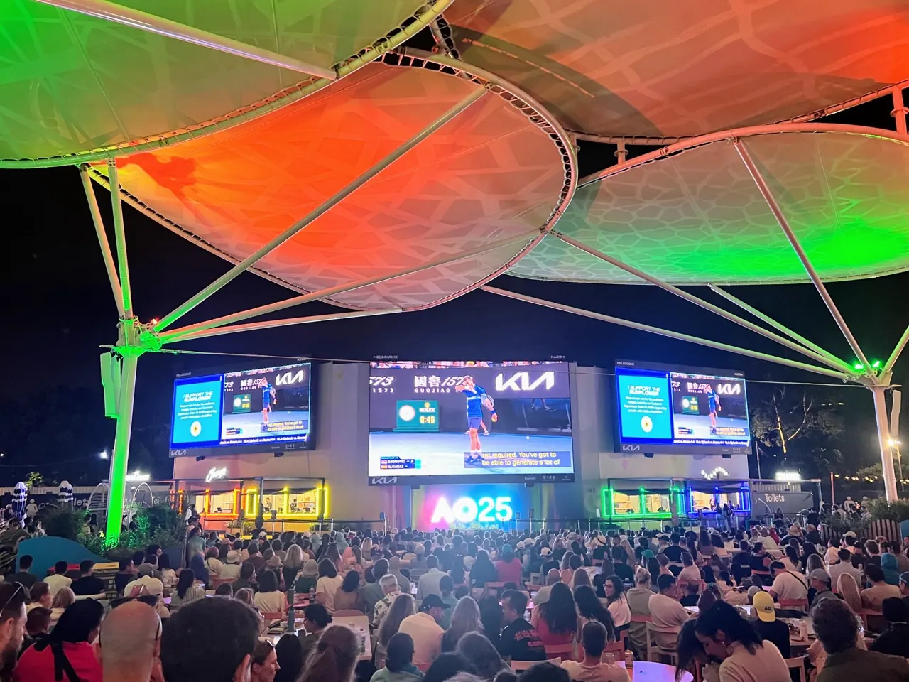 Crowds watching Australian Open 2025 coverage on outdoor screens